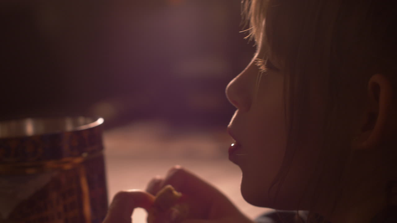 Little girl child taking cookie from a jar and happily eating it. Ambient light