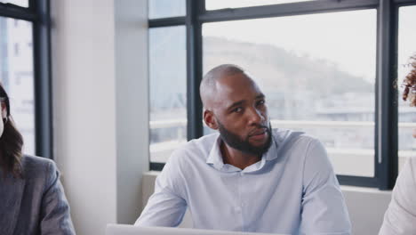 Business-team-at-a-table-in-meeting-room,-middle-aged-white-businessman-standing,-close-up,-arc-shot