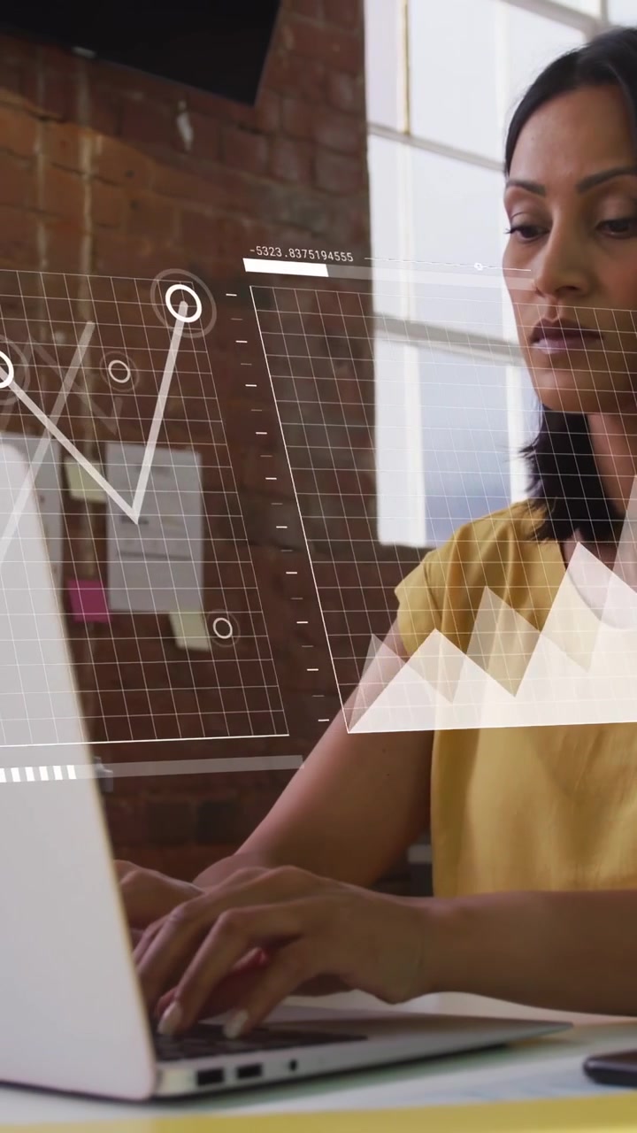Vertical video: Woman analyzing, typing, pausing, causing IT charts and world map overlaying screen
