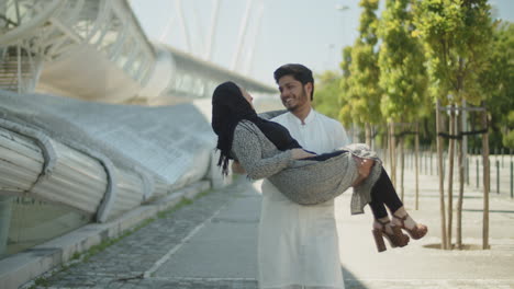 loving muslim man carrying his beautiful young wife in his arms.