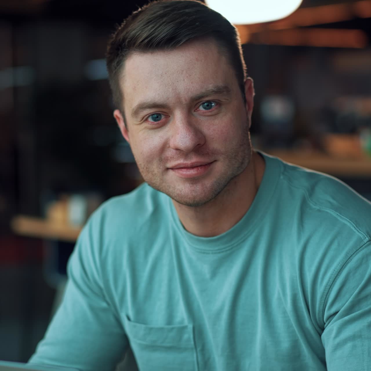 Confident blue-eyed handsome man looks into camera. Caucasian businessman puts on his glasses and starts work on his laptop