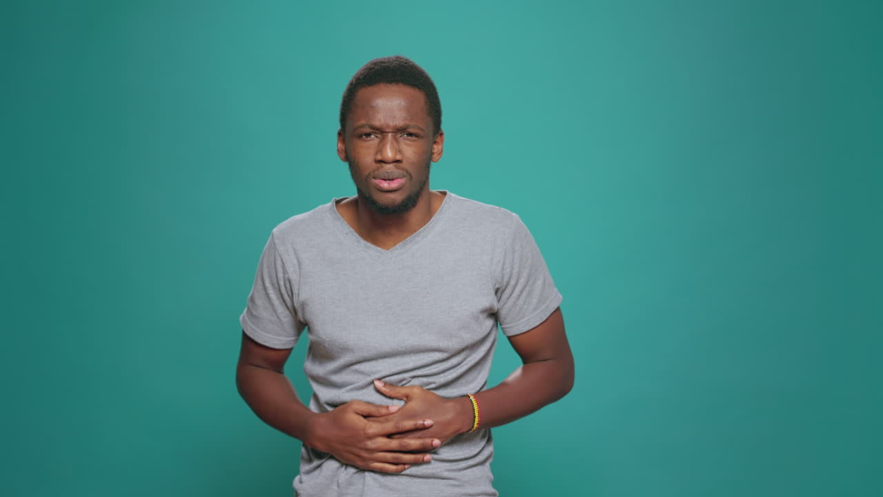Portrait of male model having stomach ache and abdominal cramp