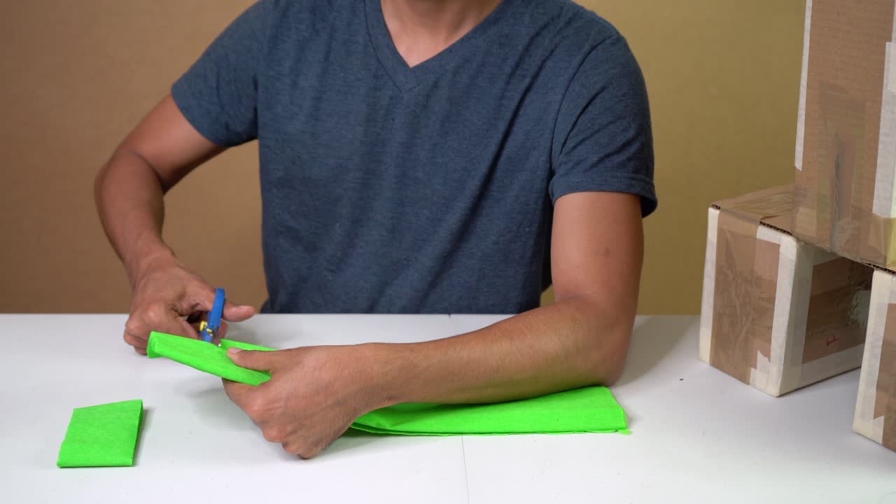 Craftsman cuts green crepe paper in relaxed workshop setting