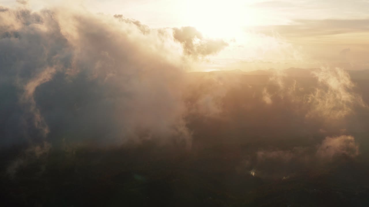 Vista aerea volando attraverso nuvole leggere, ammassate e filiformi al tramonto o all'alba dorata