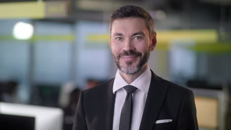 portrait of cheerful male boss with beard looking to camera and smiling. good looking caucasian man team leader in modern company office