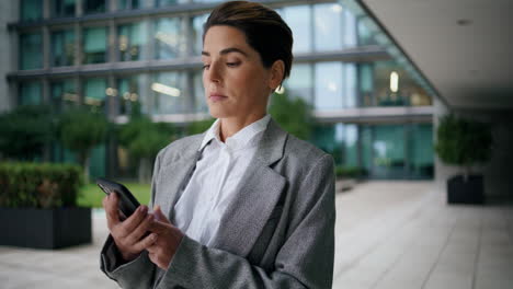 annoyed businesswoman text phone at office center. nervous executive send reply