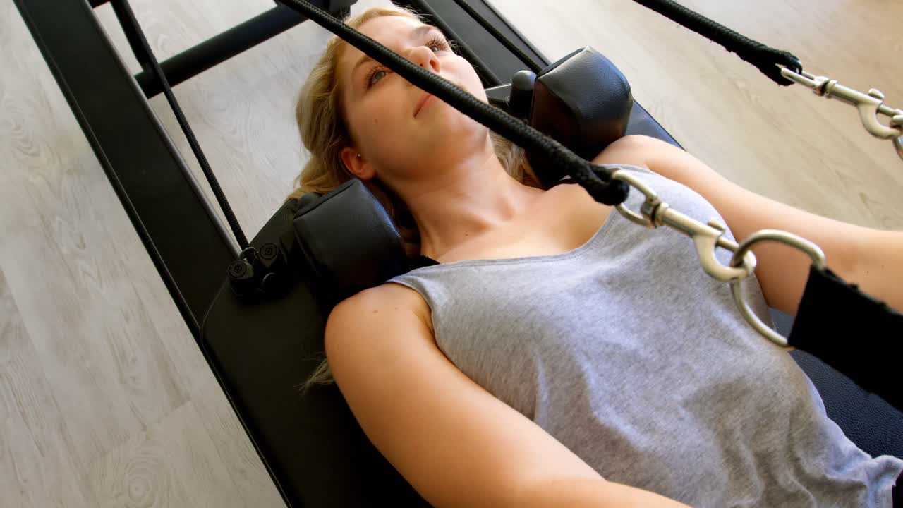 로잉 기계 4k에서 저항 밴드로 운동을 하는 여자