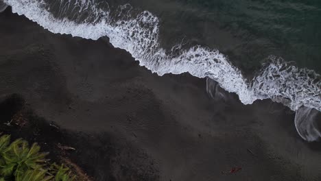 Foamy-Waves-Splashing-On-The-Black-Sand-Beach-Of-Grand-Anse-In-Guadeloupe,-France---Aerial-Top-Down