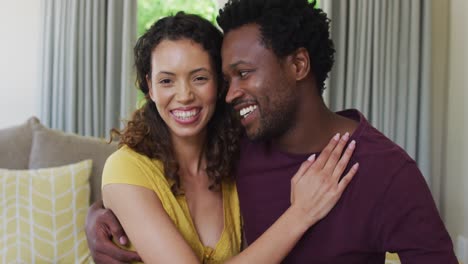 portrait of happy biracial couple looking at camera, embracing and smiling