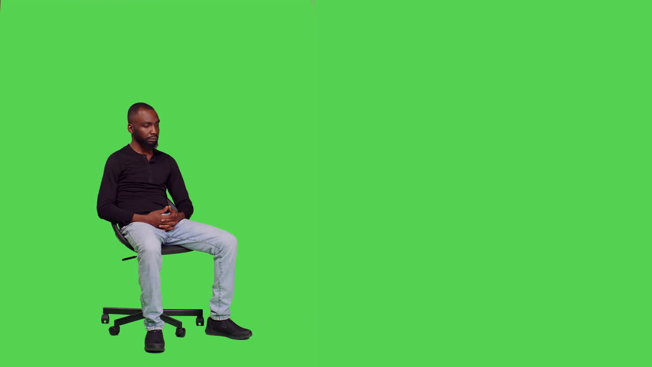 Man Sitting on Chair in Front of Green Screen