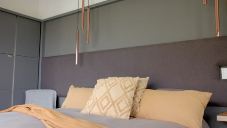 gold and beige pillows resting on neatly made bed with a grey headboard