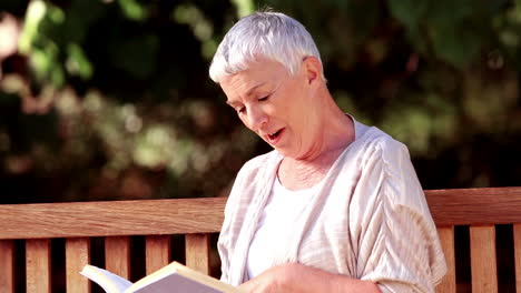 Mujer-Madura-Leyendo-Un-Libro-En-Un-Banco.