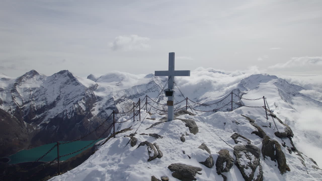태양에 의해 알프스 산 조명의 눈 덮인 정상에 신성한 정상 회담 십자가를 보여주는 무인 항공기 샷 - 궤도 샷