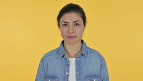 young indian woman looking at camera, yellow background