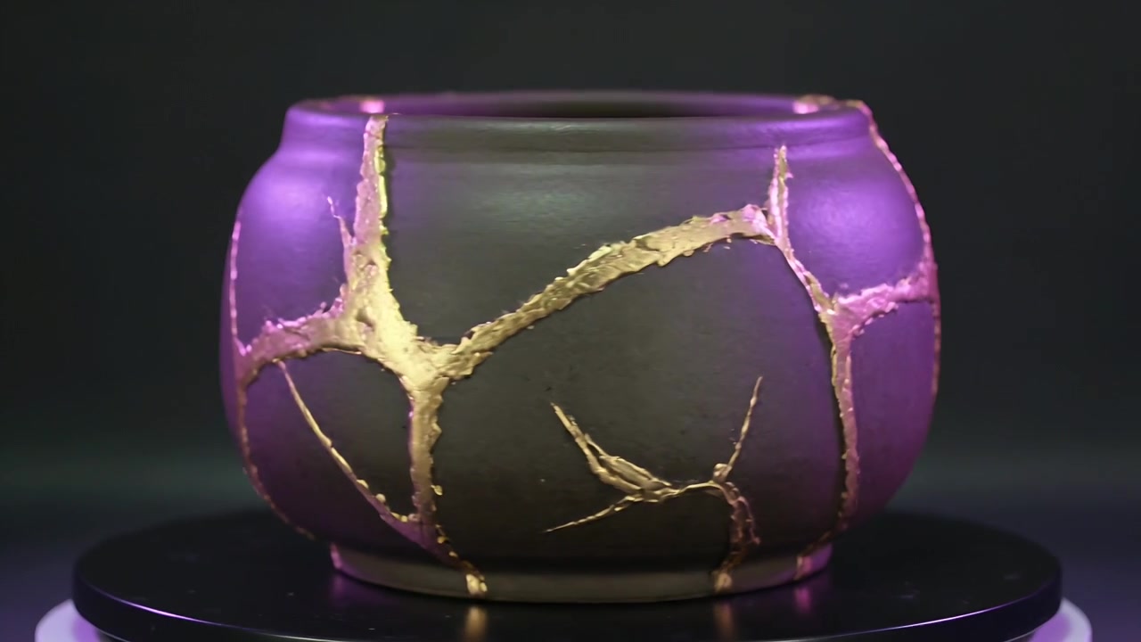 Rotating platform revealing matte ceramic pot in studio display, showing gold seams and purple rim