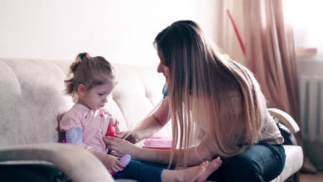 La-Joven-Madre-Y-Su-Dulce-Hija-Desempeñan-El-Papel-De-Médico-Y-Paciente.