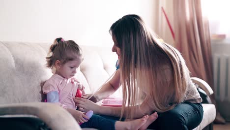 madre joven y dulce hija juegan el papel de médico y paciente