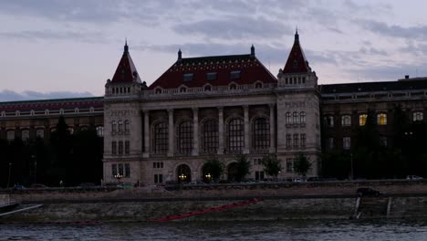 close up hand-held shot of budapest university of technology and economics building at golden hour, shot from the danube river in budapest, hungary