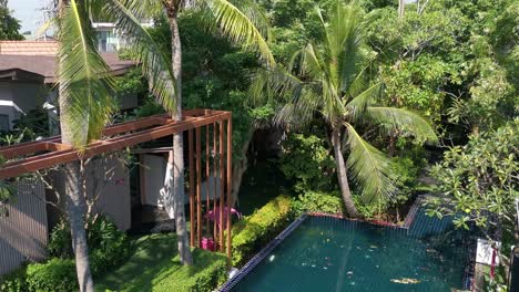 Thai-Resort-Tilt-Down-Swimming-Pool-Surrounding-Palm-Trees,-Thailand