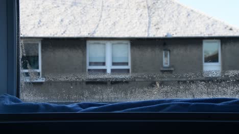 wide shot of a long blue towel trying to soak up the condensation from the window