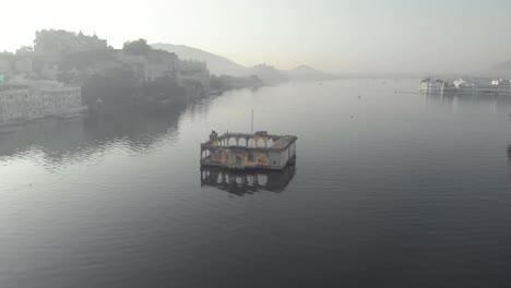 Vista-Superior-Del-Templo-Mohan-Mandir-En-El-Lago-Pichola,-En-Udaipur,-Rajasthan,-India---Sobrevuelo-Aéreo-De-ángulo-Bajo