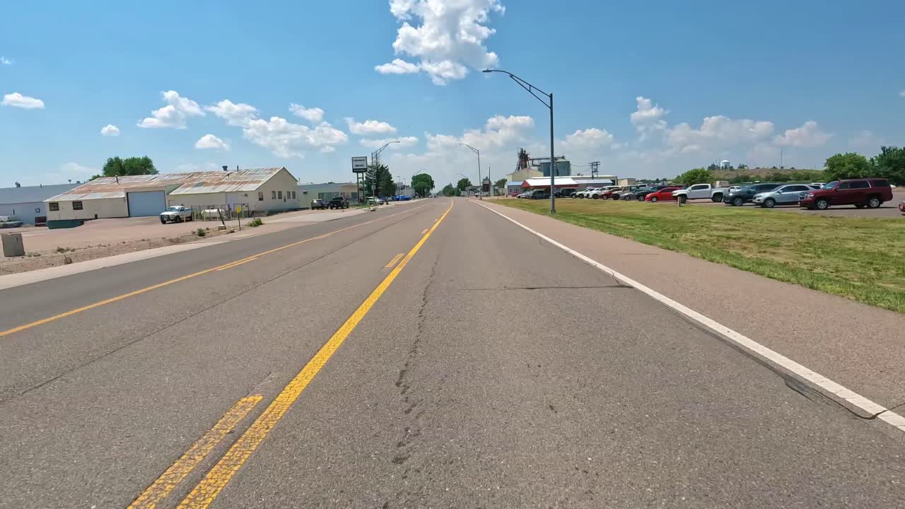 POV - Driving on a traditional main street in downtown of a quaint Midwestern town; driving past an Auto Dealership and a Feed and Animal Supply; hometown