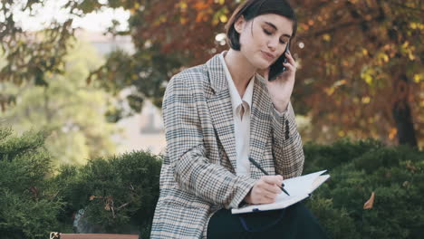 female entrepreneur writing in notepad while resting outdoor.