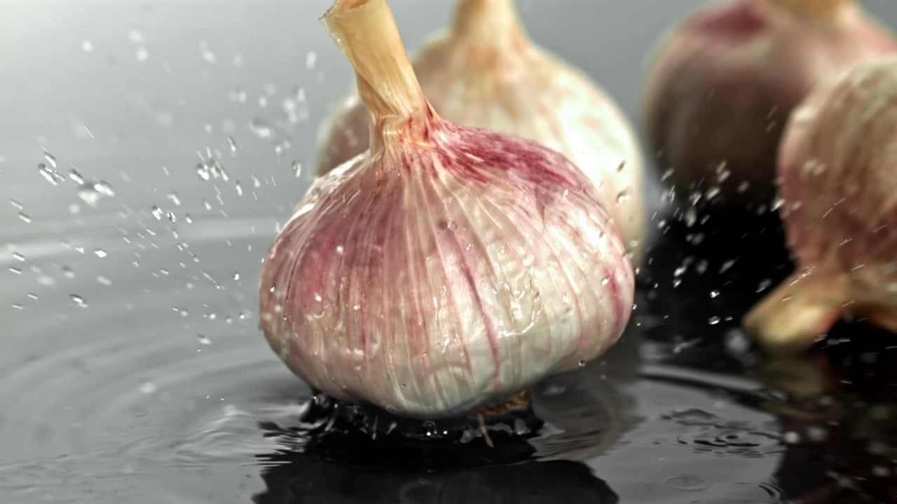 Bulbo d'aglio fresco che cade nell'acqua al rallentatore.