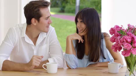 laughing young adult couple sitting at table