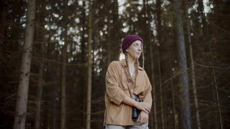 turista femenina con binoculares mirando alrededor en el bosque