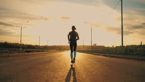 sportswoman is running outdoors rear view of sporty female figure against sunset sun