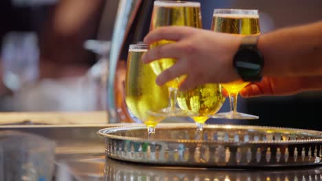 Four-goldened-coloured-beers-are-on-a-silver-tray