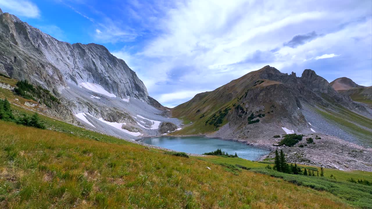 Summer late afternoon Capitol Lake Capitol Peak 14er wilderness landscape view blue sky clouds high elevation tundra snow melt pan Colorado Elk Mountain Range Aspen Snowmass Rocky Mountains pan left
