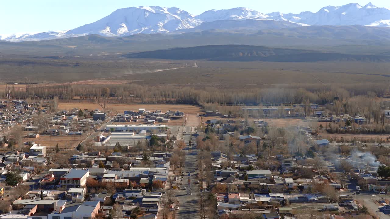 Slow drone shot over Malargüe, Mendoza, Argentina, with a clear view of the city’s grid layout and Cerro Diamante rising in the Andes range beyond the semi-arid plain under blue sky.
