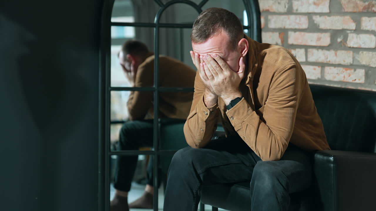 Caucasian man dealing with some problems. Man sits in the armchair holding by the head and leans back.