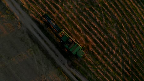 agriculture-machine-standing-in-field,-people-walking-around-and-cleaning-it,-making-dust-clouds,-camera-is-going-down