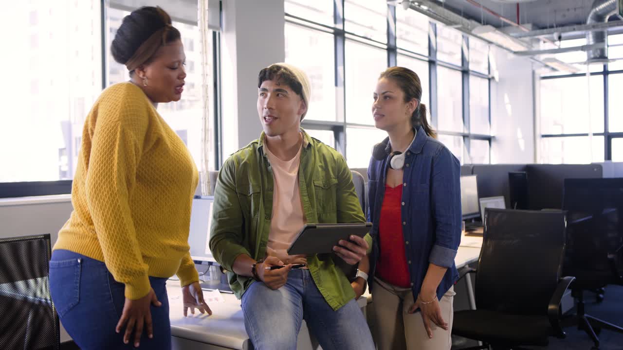 Diverse collega's lanceren een design-app op een tablet, annoteren mockups en verfijnen de lay-out op kantoor