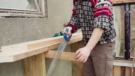 Man-Using-Hand-Saw-In-Cutting-Woods---Man-Building-A-Greenhouse---Close-Up