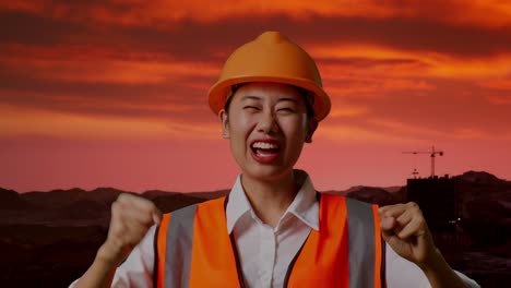 primer plano de ingeniera asiática con casco de seguridad gritando gol y bailando celebrando en el sitio de construcción, maquinaria de minería