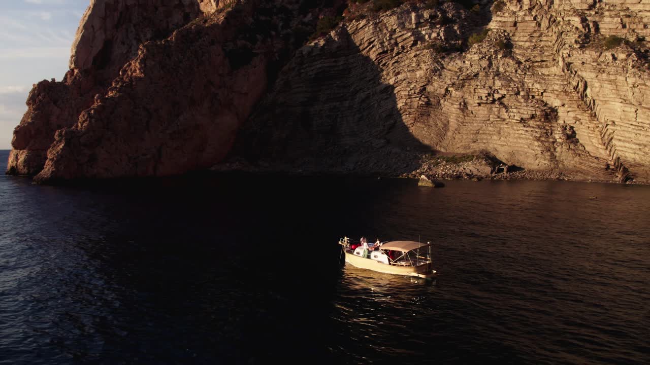 Group of friends on a boat in the bay, sunset seaside ambience