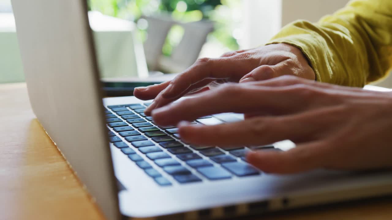 sección media de una mujer caucásica usando una computadora portátil y trabajando desde casa