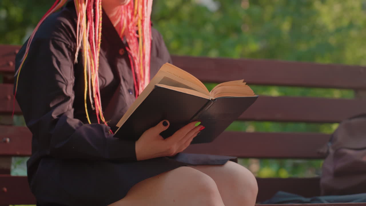 lectura individual al aire libre, persona disfrutando de una lectura tranquila en un parque, persona solitaria relajándose con un libro en el exterior, persona sentada tranquilamente leyendo en un entorno natural durante el día