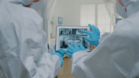 dental doctors examining x ray of teeth on tablet screen