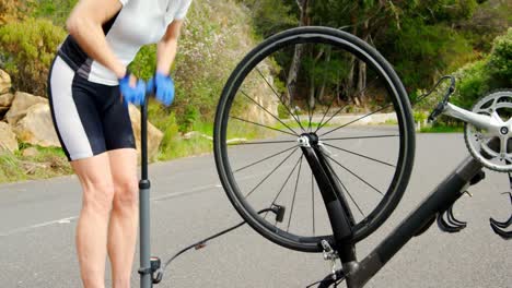 Atleta-De-Mediana-Edad-Bombeando-Un-Neumático-De-Bicicleta-Con-Una-Bomba-De-Bicicleta-En-Una-Carretera-Rural-4k