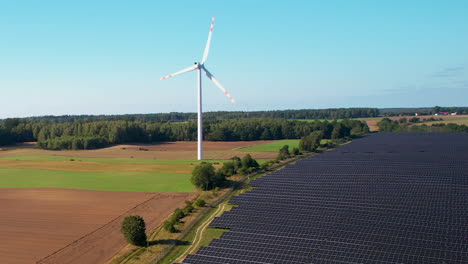 Vista-Aérea-De-Molinos-De-Viento-Giratorios-Junto-A-Una-Granja-De-Paneles-Solares-A-Gran-Escala