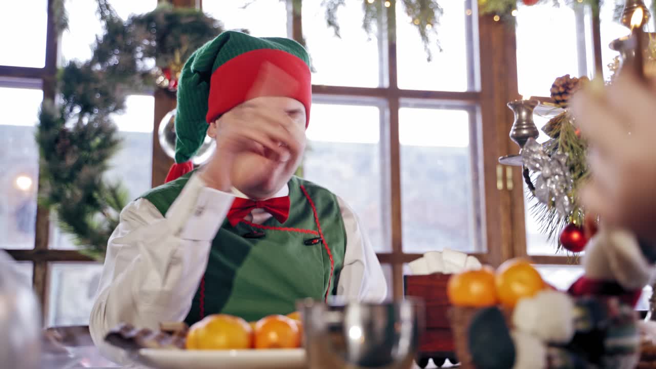 Male elf eating sweets. Portrait of male elf eating sweets at table