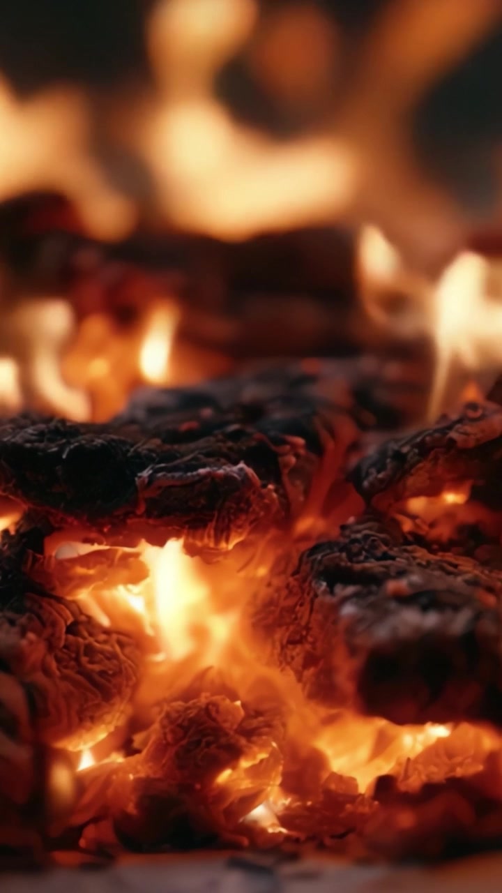 Braci affascinanti: un'esplorazione ravvicinata di fiamme incandescenti e carboni al loro culmine ardente, creando un'esperienza visiva ipnotizzante di calore e luce.