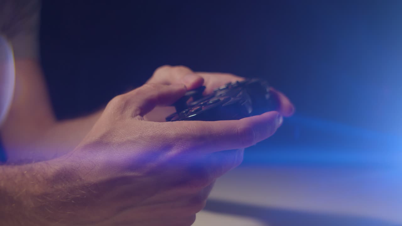 jugar videojuegos en una habitación oscura con un destello de lente anamórfico en los botones de un controlador pequeño que reproduce destellos lentos