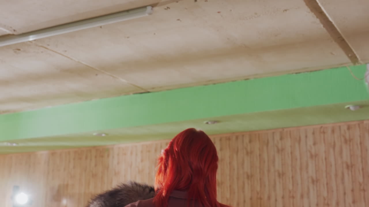 Donna che abbraccia calorosamente un procione in un ambiente interno, custode dai capelli rossi che abbraccia un grande procione lanuginoso sulla spalla, carezze delicate e fiducia reciproca, primo piano sulla morbida pelliccia, calda illuminazione da studio, legame di compassione, salvataggio