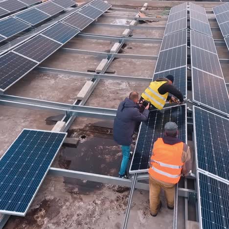 installation of solar panels on a flat roof. workers in protective uniform installing sunny batteries in rows. clean energy from the sun. aerial view.
